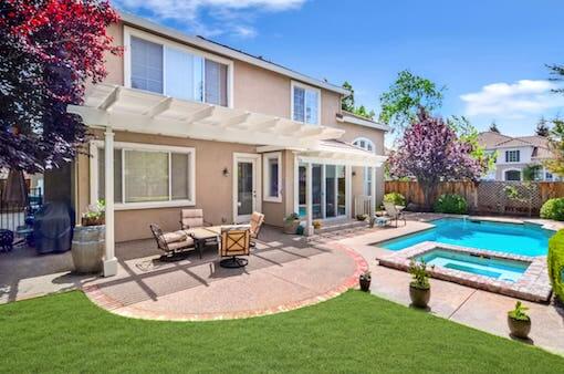 An image of large cream coloured house with swimming pool