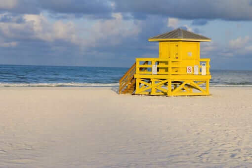 A yellow wooden lifeguard hut on an empty morning beach